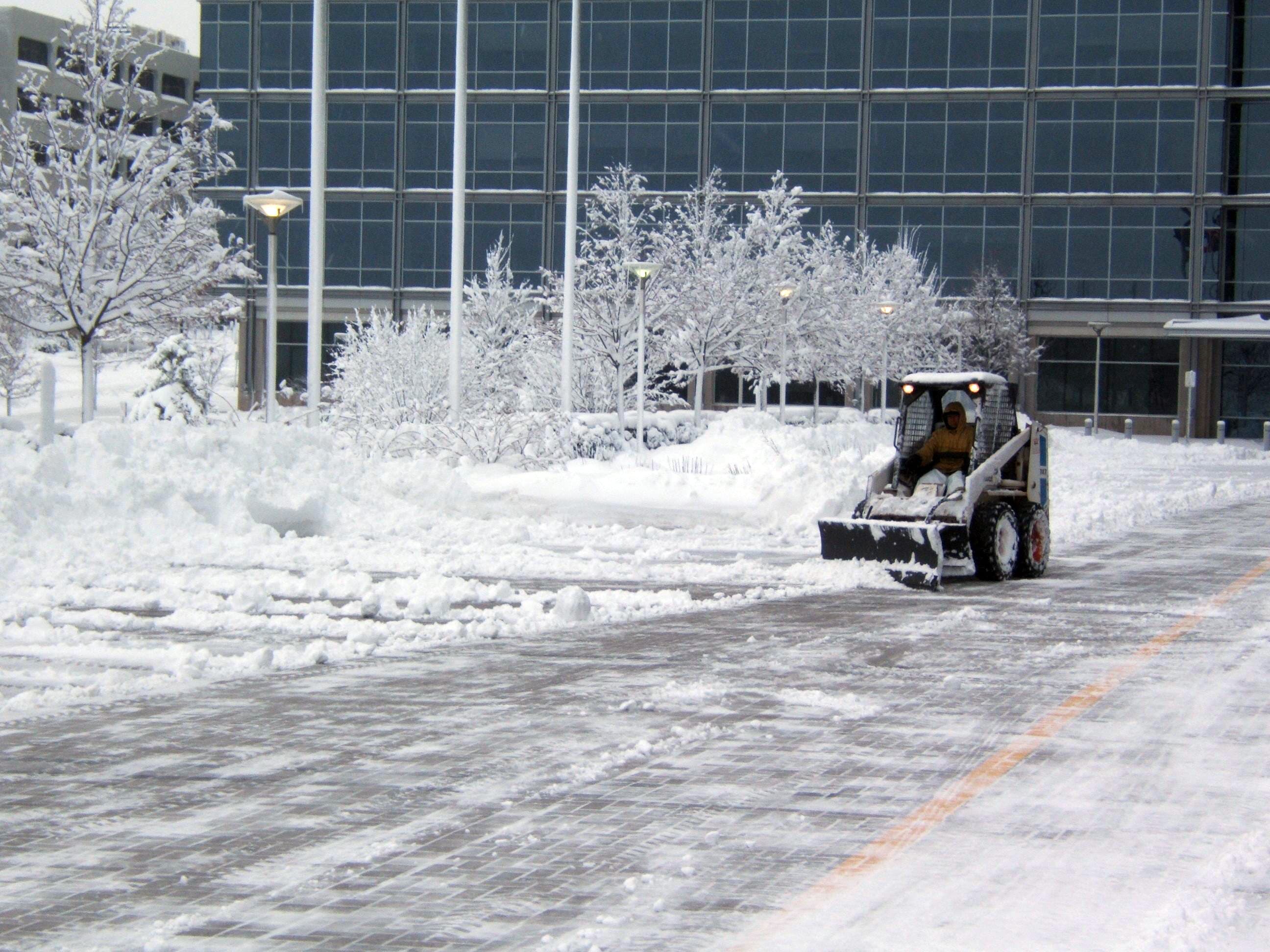 CPM crew clearing a commercial parking lot with a skid steer after a snowstorm